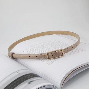Detail of slim beige leather belt with a minimalist golden square metal buckle