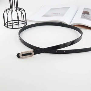 Women's black patent leather belt with sparkling rhinestone oval buckle on white desk