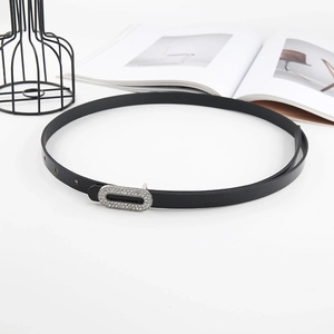 Close-up of black patent leather belt with sparkling silver rhinestone oval buckle on a magazine