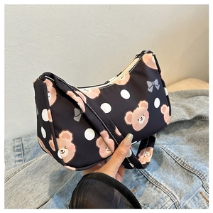 Detail view of the black crescent shoulder bag with cute brown bear and bow print details