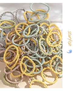 Pile of colorful elastic hair ties for kids featuring a twisted rope texture in soft colors