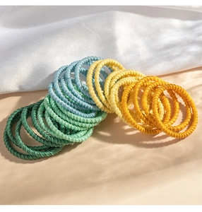 Close-up of colorful elastic woven hair ties in green, blue and yellow on silk fabric