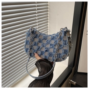 Close-up of blue checkerboard denim handbag featuring frayed edges and silver chain strap