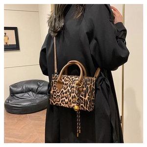 Fashionable leopard print large tote bag with brown leather handles and gold bell charm