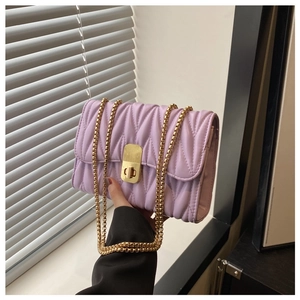 Detail view of light purple quilted chain bag with elegant gold metal clasp and texture