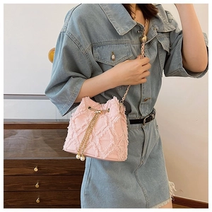 Pink denim drawstring bucket bag with gold chain strap and pearl charm on a model