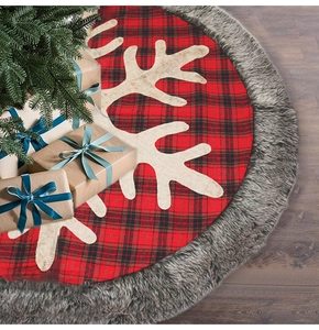 Detail of red and black plaid Christmas tree skirt with white snowflake patterns and fur trim