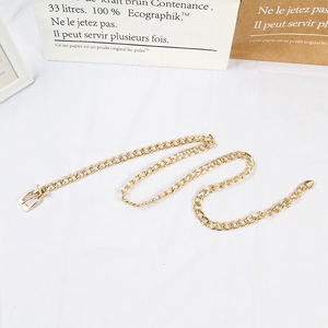 Detailed view of a gold metallic chain belt with interlocking links on a white backdrop