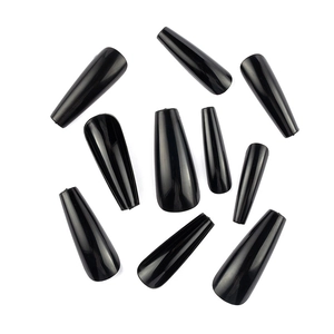 Flat lay of glossy black long coffin press-on nails scattered on white background
