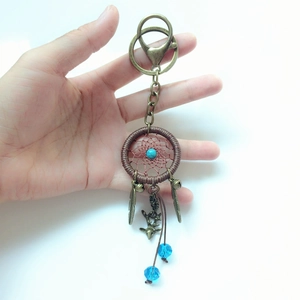Detail of handmade blue bead dreamcatcher keychain with bronze feather and deer head charms