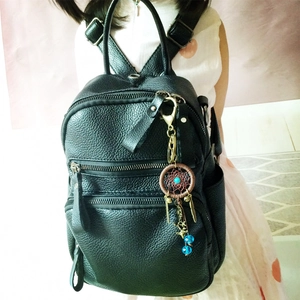 Detail of dreamcatcher keychain with blue beads on a black leather backpack for girls
