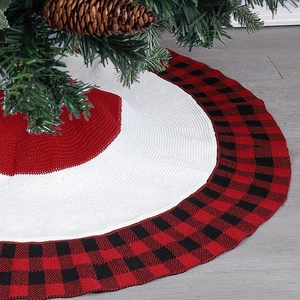Detail view of red and black plaid knitted Christmas tree skirt on grey wooden floor