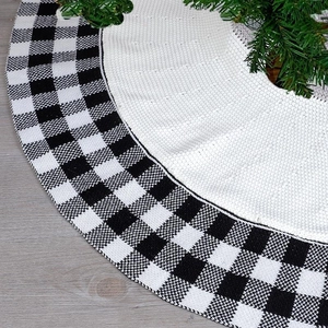 Close-up of black and white buffalo plaid knitted Christmas tree skirt on wooden floor