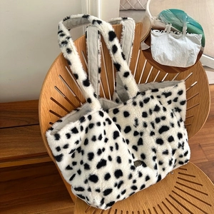 Close-up of reversible cow print plush tote bag with white canvas interior and brand logo