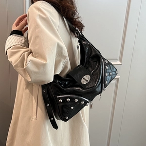 Detailed view of a black moto-style crossbody bag with studs and zipper on a model