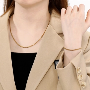 Golden stainless steel Cuban chain necklace and bracelet jewelry set worn by a model