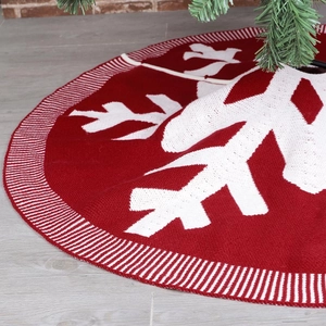 Close-up of burgundy knitted Christmas tree skirt with white snowflake patterns and textures