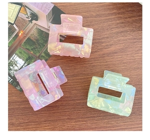 Detailed shot of three rectangular hair clips in pink, purple, and green with shell patterns