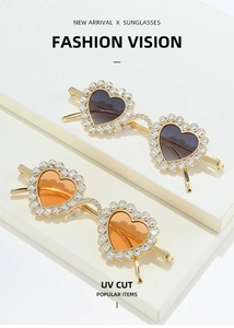 Détail de lunettes de soleil coeur en métal avec strass et verres gris et orange