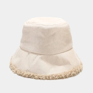 Dettaglio del cappello a secchiello invernale in tessuto beige con bordo in lana d'agnello