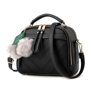 Fashionable black V-quilted faux leather crossbody bag with cherry pom-pom charm
