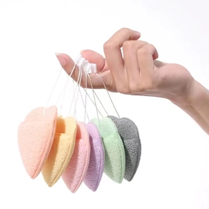 Hand holding colorful heart-shaped facial cleansing sponges with hanging loops