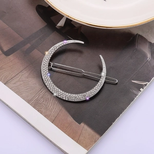 Barrette à cheveux lune argentée avec strass blancs sur une page de magazine