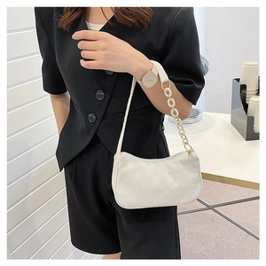 Detail view of a white corduroy shoulder bag with an acrylic chain and gold-tone hardware
