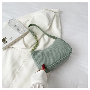 Detail of green corduroy small square bag with chain strap on a white blazer