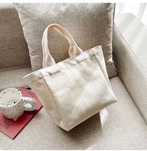 Close-up of a small beige canvas tote bag on a sofa with a lifestyle setting