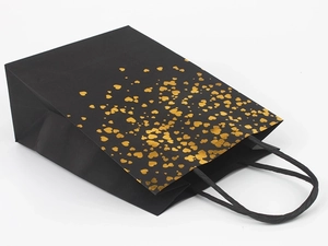 Detail of premium black paper gift bag featuring shiny gold foil heart patterns and rope handles
