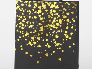 Detail of premium black paper gift bag featuring elegant gold foil heart patterns