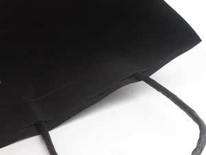 Detailed close-up of matte black paper gift bag with matching twisted paper rope handles