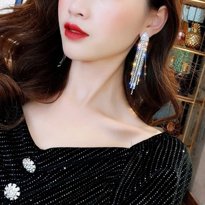 Close-up of elegant long silver tassel earrings with sparkling rhinestones on a model