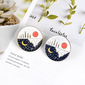Detail of round enamel pins featuring mountain landscapes with sun and moon designs