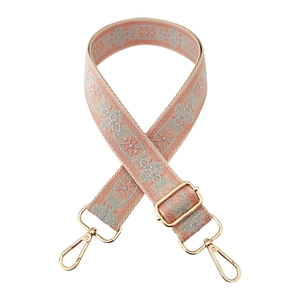 Detail of pink ethnic embroidered purse strap with golden hooks and floral patterns