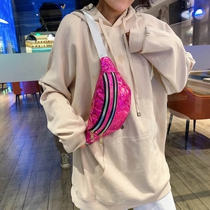 Detail of pink laser waist bag with adjustable white strap worn cross-body in a cafe