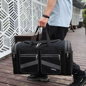 Large black foldable travel duffel bag with multi-pockets shown in outdoor scenery