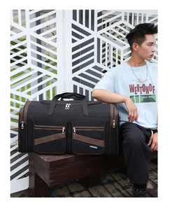 Detail of large black travel bag with brown trim and front zipper pockets outdoors