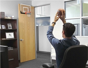 Action shot of an indoor mini basketball hoop being used in a modern office setting