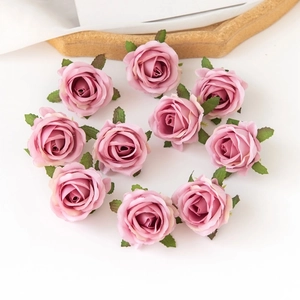 Primer plano de diez cabezas de rosas de seda rosa artificial con hojas sobre blanco