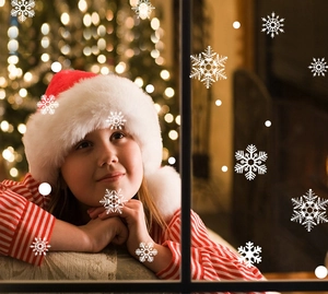 Close-up of white snowflake window clings with a child by the festive Christmas tree