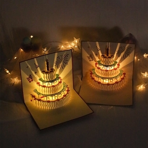Macro shot of 3D pop-up birthday card with glowing LED candles and cake details