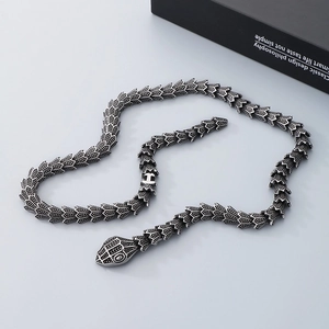 Macro shot of silver snake pendant on grey background with black branded gift box