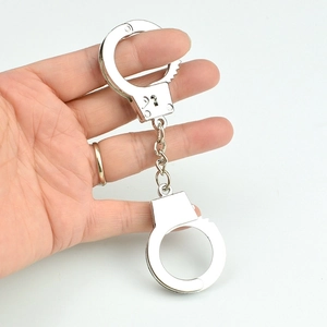 Miniature silver metal handcuff keychain displayed on finger with a sleek finish