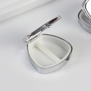 Portable round silver metal pill box with white two-compartment internal divider
