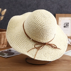 Detailed texture of straw sun hat featuring a stylish brown leather bow decoration