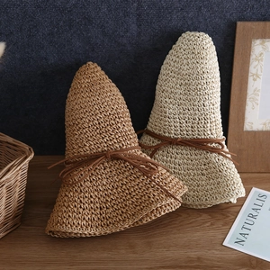 Detail view of handmade woven straw sun hats with leather cord bow and natural texture