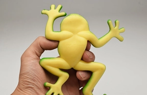 Close-up of a stretchable yellow-green rubber frog toy being squeezed by hand