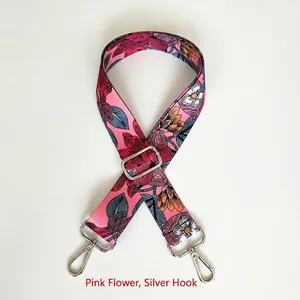 Detail view of woven floral bag strap in pink with adjustable silver metal hooks